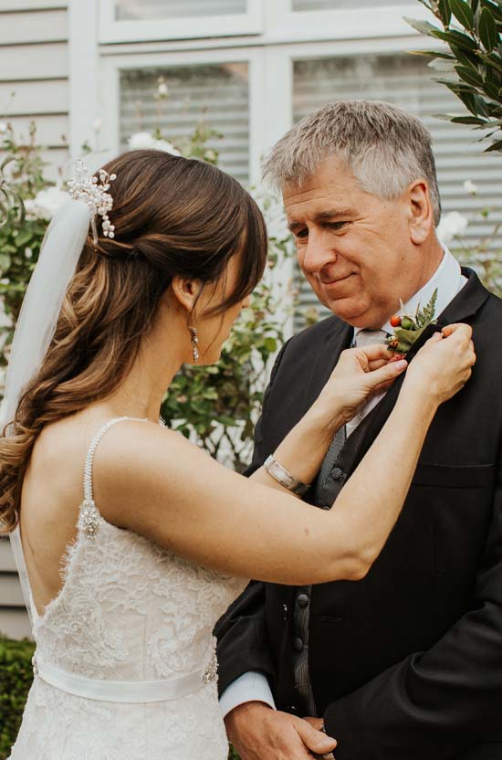 Bride pinning a button hole on her father